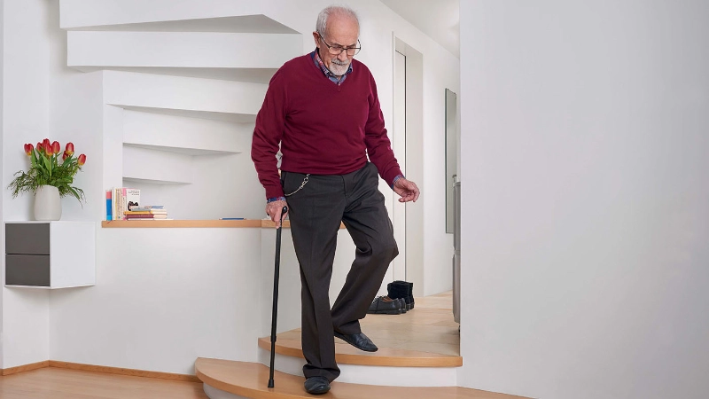 Ein Senior läuft mit einem Stock die Treppe herunter