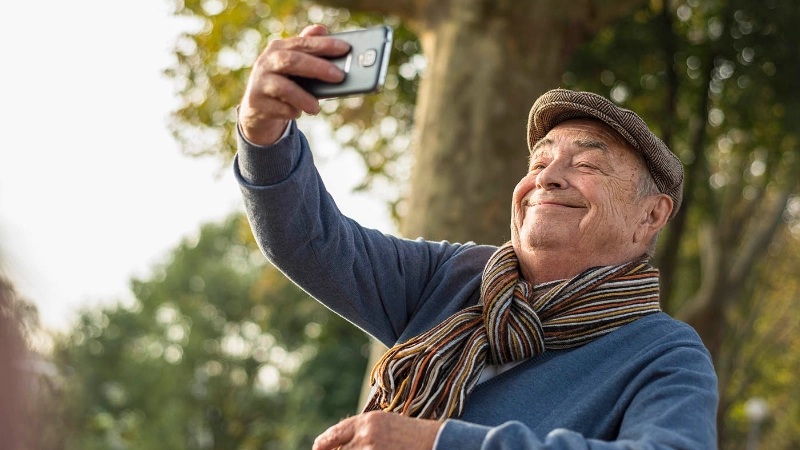 Ein älterer Mann macht ein Selfie von sich selber mit dem Handy
