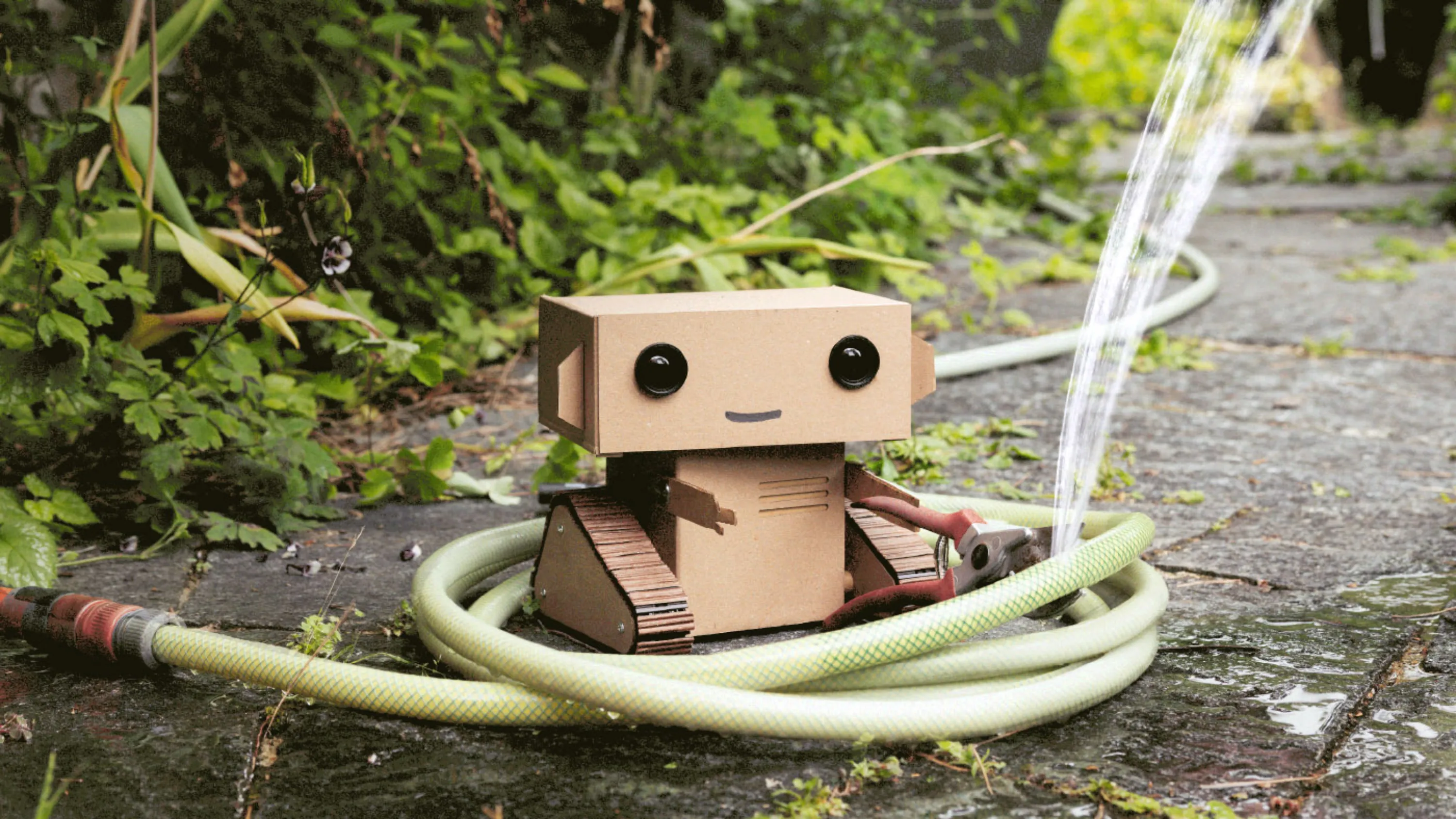 Titelbild des Leistungsberichts mit dem Karton-Roboter Robi, der bei einem Wasserschlauch ein Loch reinschneidet