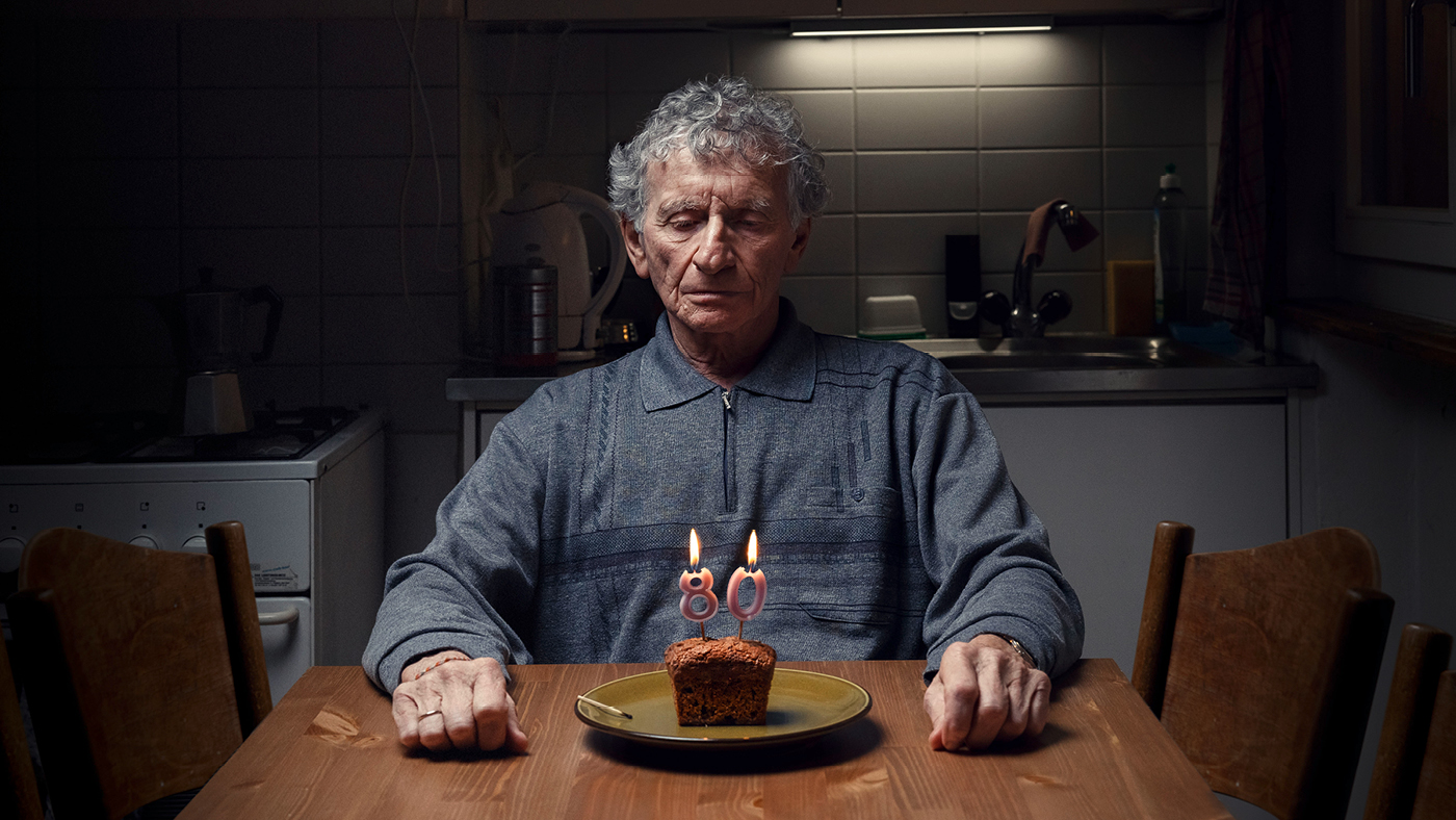 Une personne âgée est assise devant un gâteau d'anniversaire